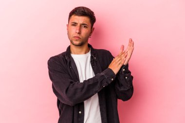 Sarı arka planda izole edilmiş, enerjik ve rahat hisseden elleri ovuşturan, kendine güvenen beyaz dövmeli genç bir adam..