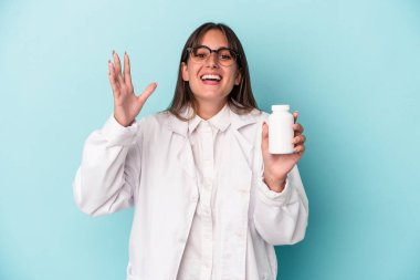 Mavi arka planda hapları tutan genç bir eczacı kadın hoş bir sürprizle karşılaşıyor, heyecanlı ve el kaldırıyor..