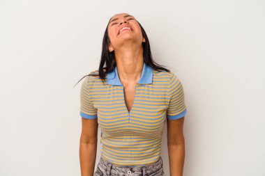 Beyaz arka planda izole edilmiş genç Latin bir kadın gevşemiş ve mutlu bir şekilde gülüyor, boynunda dişlerini gösteriyor..