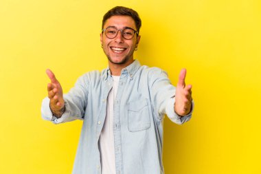 Sarı arka planda dövmeleri olan beyaz bir adam kameraya sarıldığı için kendini güvende hissediyor..