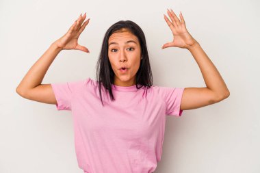 Beyaz arka planda izole edilmiş genç Latin bir kadın zaferi ya da başarıyı kutluyor, şaşırıyor ve şok oluyor..