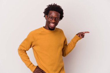 Beyaz arka planda izole edilmiş genç bir Afrikalı Amerikalı işaret parmağıyla işaret ederek gülümsüyor..