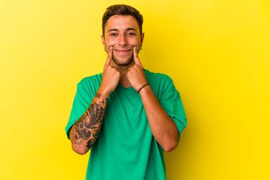 Sarı arka planda dövmeleri olan beyaz bir adam iki seçenek arasında kuşkulanıyor..