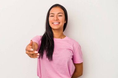 Beyaz arka planda izole edilmiş genç Latin bir kadın selamlama jesti olarak kameraya elini uzatıyor..