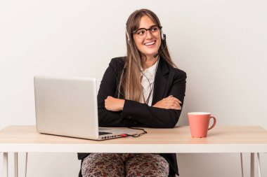 Beyaz arka planda yalnız başına seyahat eden beyaz bir kadın. Kollarını kavuşturup gülümsüyor..