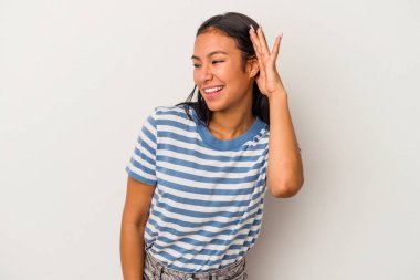 Beyaz arka planda izole edilmiş genç Latin bir kadın bir dedikoduyu dinlemeye çalışıyor..