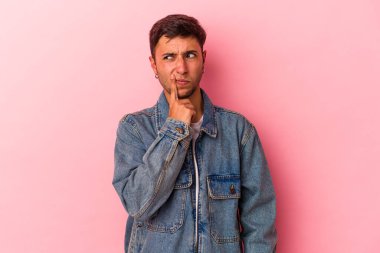 Sarı arka planda izole edilmiş, şüpheli ve şüpheci bir ifadeyle yan bakan beyaz dövmeli genç bir adam..