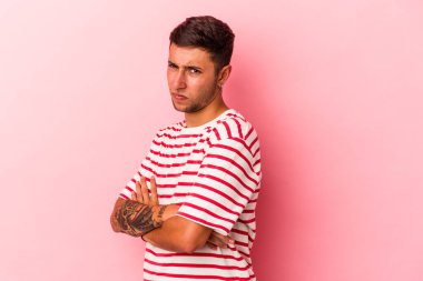 Sarı arka planda izole edilmiş, hoşnutsuzca kaşlarını çatmış, kollarını kavuşturmuş, beyaz, genç bir adam..