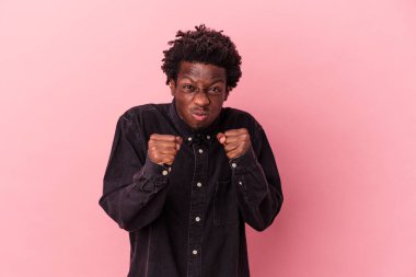 Pembe arka planda izole edilmiş genç Afro-Amerikalı adam yumruğunu kameraya gösteriyor, agresif bir yüz ifadesi var..
