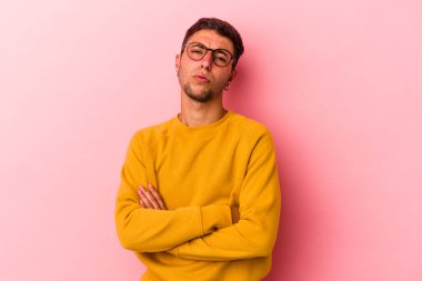 Sarı arka planda izole edilmiş dövmeleri olan genç beyaz bir adam tekrarlanan bir görevden yoruldu..