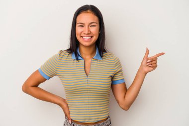 Beyaz arka planda izole edilmiş genç Latin kadın işaret parmağıyla işaret ederek gülümsüyor..