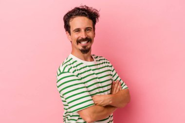 Pembe arka planda izole edilmiş genç beyaz adam mutlu, güler yüzlü ve neşeli.