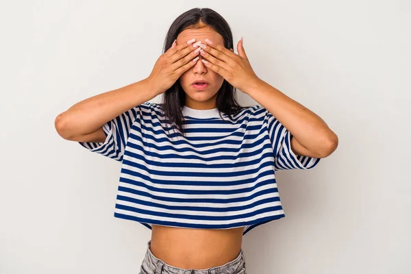 Beyaz arka planda izole edilmiş genç Latin kadın elleriyle gözlerini kapatmaktan korkuyor..