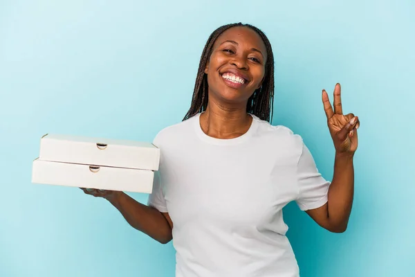 青を基調としたピザを持つ若いアフリカ系アメリカ人女性喜びと屈託のない指で平和のシンボルを示す — ストック写真