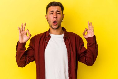 Sarı arka planda izole edilmiş dövmeleri olan genç beyaz adam sıkı çalışma gününden sonra rahatlıyor. Yoga yapıyor..