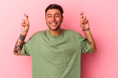 Sarı arka planda, şans dilemek için izole edilmiş dövmeleri olan genç beyaz bir adam.