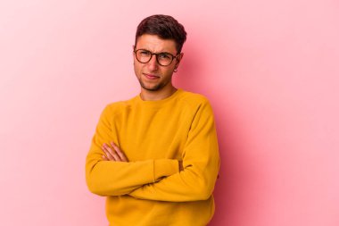 Sarı arka planda izole edilmiş beyaz dövmeli genç adam alaycı bir ifadeyle kameraya bakıyor..