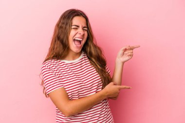 Pembe arka planda izole edilmiş genç beyaz kadın işaret parmaklarıyla fotokopi alanını işaret ederek heyecan ve arzusunu ifade ediyor..