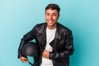 Mavi arka planda kask tutan genç bisikletçi gülüyor ve eğleniyor..