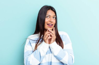 Genç Venezuelalı kadın mavi arka planda izole edilmiş bir plan kuruyor..