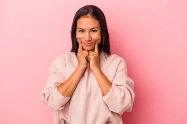 Pembe arka planda izole edilmiş genç Latin kadın iki seçenek arasında şüphe duyuyor.