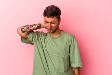 Sarı arka planda izole edilmiş beyaz dövmeli genç bir adam sabit yaşam tarzından dolayı boyun ağrısı çekiyor..