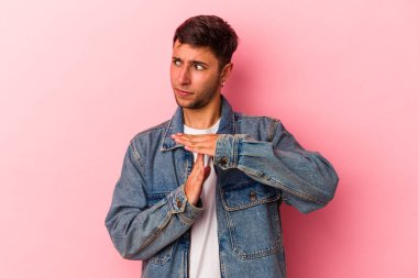 Sarı arka planda izole edilmiş dövmeleri olan genç beyaz bir adam, bir zaman aşımı hareketi gösteriyor..