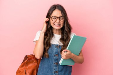 Young caucasian student woman isolated on pink background covering ears with hands.