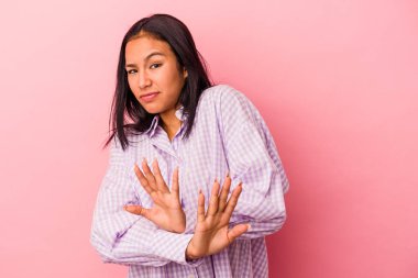 Pembe arka planda izole edilmiş genç Latin kadın inkar jesti yapıyor.