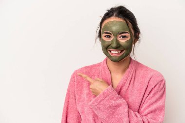 Young caucasian woman wearing a facial mask isolated on white background smiling and pointing aside, showing something at blank space.