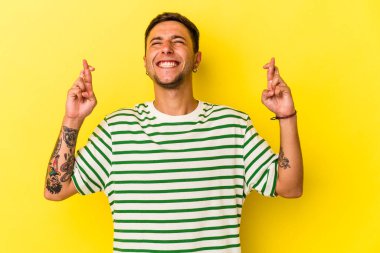 Sarı arka planda, şans dilemek için izole edilmiş dövmeleri olan genç beyaz bir adam.