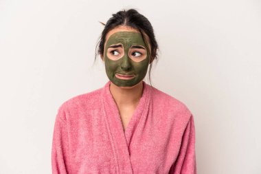Young caucasian woman wearing a facial mask isolated on white background confused, feels doubtful and unsure.