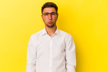 Sarı arka planda izole edilmiş beyaz dövmeli genç bir adam üzgün, ciddi yüzlü, mutsuz ve hoşnutsuz..