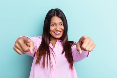 Genç Venezuelalı bir kadın, mavi arka planda soyutlanmış, mutlu bir şekilde gülümsüyor..