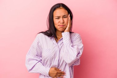 Pembe arka planda izole edilmiş genç Latin kadın yanakları patlatıyor, yorgun bir ifadesi var. Yüz ifadesi kavramı.