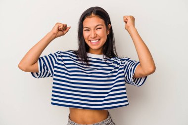 Beyaz arka planda izole edilmiş genç Latin bir kadın zaferi, tutkuyu ve coşkuyu, mutlu ifadeyi kutluyor..