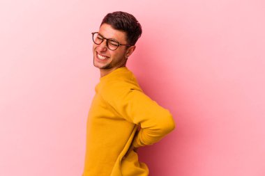 Sarı arka planda, sırt ağrısı çeken, dövmeli, beyaz bir genç..