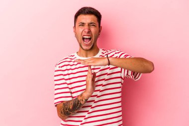 Sarı arka planda izole edilmiş dövmeleri olan genç beyaz bir adam, bir zaman aşımı hareketi gösteriyor..