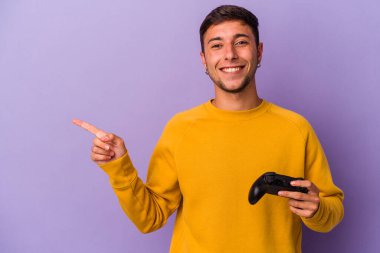 Mor arka planda izole edilmiş, gülümseyen ve işaret eden, boş alanda bir şey gösteren beyaz bir adam..