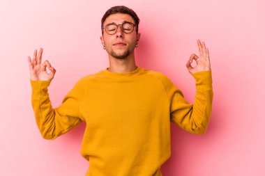 Sarı arka planda izole edilmiş dövmeleri olan genç beyaz adam sıkı çalışma gününden sonra rahatlıyor. Yoga yapıyor..