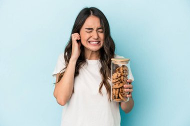 Beyaz bir kadın, sarı arka planda, kulaklarını elleriyle kapatarak hareket ediyor..