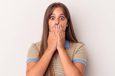 Beyaz arka planda izole edilmiş genç beyaz kadın elleriyle ağzını kapatırken şok oldu..
