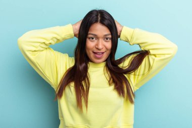 Genç Venezuelalı bir kadın mavi arka planda izole edilmiş bağırıyor, çok heyecanlı, tutkulu, bir şeyden memnun..