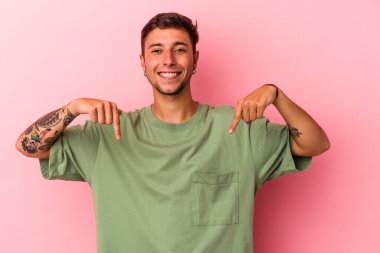 Sarı arka planda izole edilmiş dövmeleri olan beyaz bir genç. Parmakları aşağıda, olumlu hisler içinde..