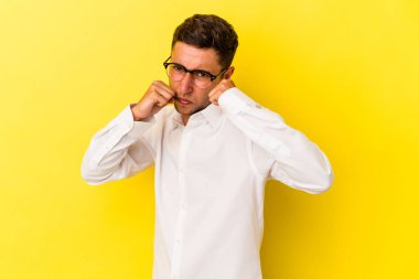 Sarı arka planda izole edilmiş dövmeleri olan genç beyaz bir adam bir tartışma yüzünden yumruk, öfke, kavga atıyor, boks yapıyor..