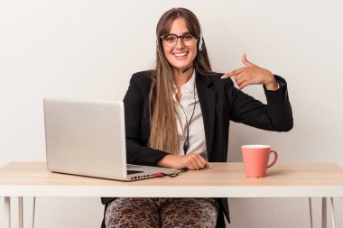 Beyaz arka planda yalnız başına seyahat eden beyaz tenli genç bir kadın gömlek fotokopi odasını işaret ediyor, gururlu ve kendinden emin.