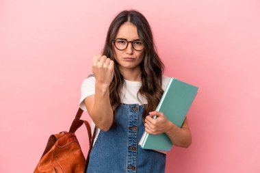 Young caucasian student woman isolated on pink background showing fist to camera, aggressive facial expression.