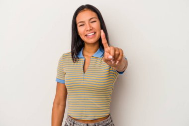 Beyaz arka planda izole edilmiş genç Latin kadın bir numarayı parmağıyla gösteriyor..