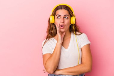 Pembe arka planda izole edilmiş müzik dinleyen beyaz bir kadın gizli bir sıcak fren haberi veriyor ve yana bakıyor.