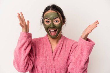 Young caucasian woman wearing a facial mask isolated on white background receiving a pleasant surprise, excited and raising hands.